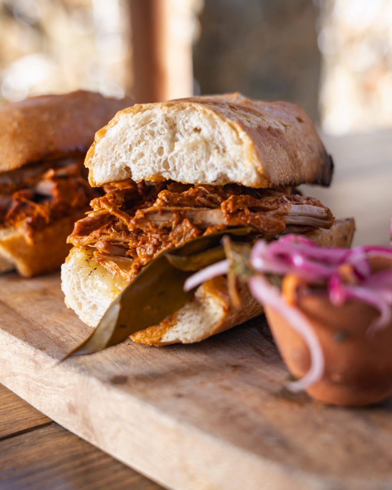 Panini de cochinita pibil con cebolla morada y hoja de laurel.