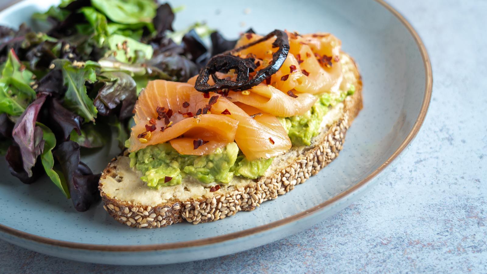 Tostada de salmón ahumado con aguacate y brotes verdes.