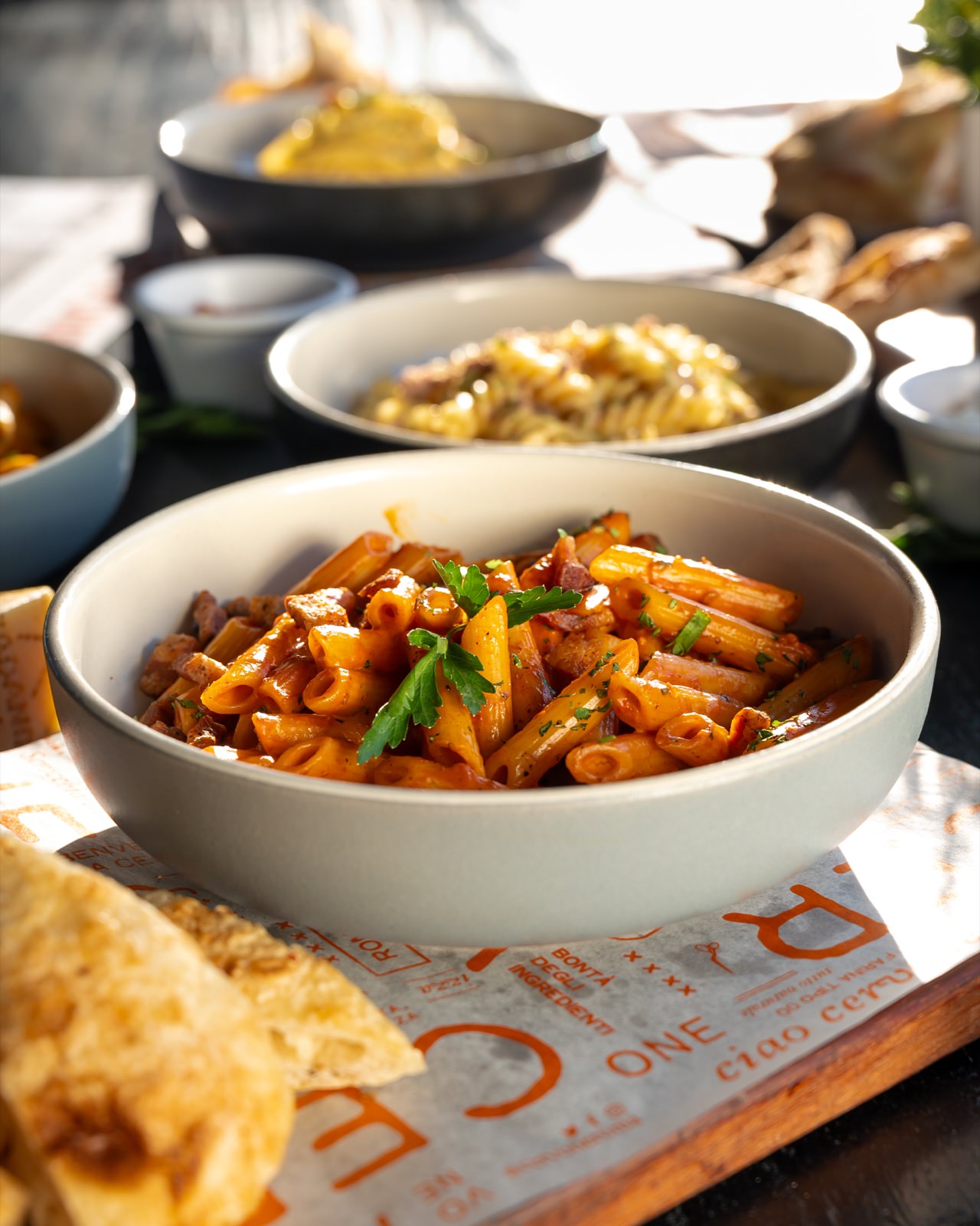 Plato de pasta corta en salsa roja con albahaca fresca.