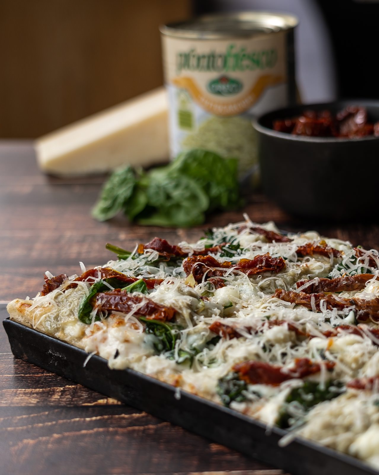 Pizza romana con queso gratinado, tomates secos y albahaca fresca.